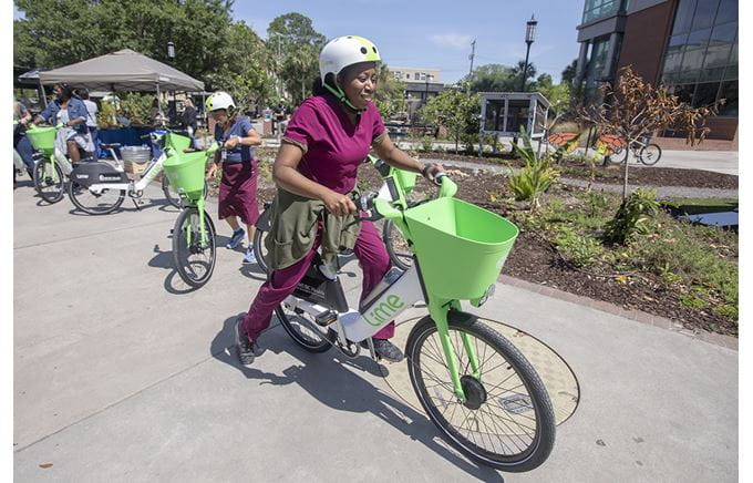 A woman in scrubs rides an electric bike